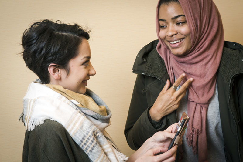 Two women talking with one another and smiling.