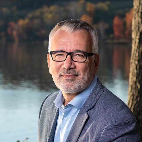 Headshto photo of Alp Ozerdem smiling in front of water