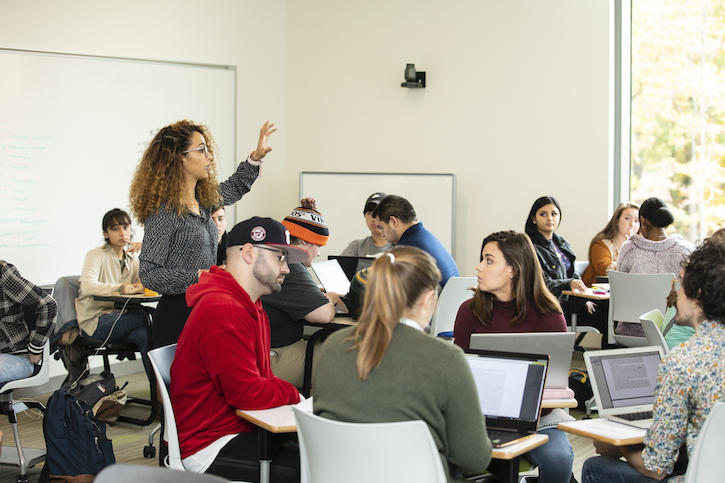 Woman standing in front of a group of students with expressive arms providing instruction