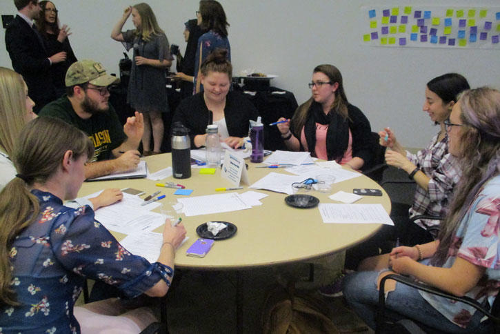 Students seated around a table, having a discussion.