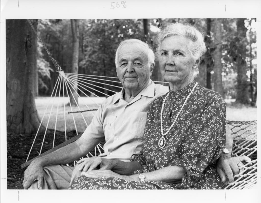 black and white photo of married couple on a hammock in a wooded area