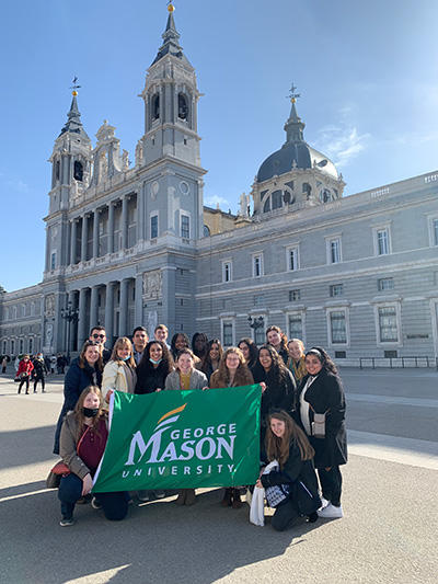 Students holding a GMU banner in front of a historical building