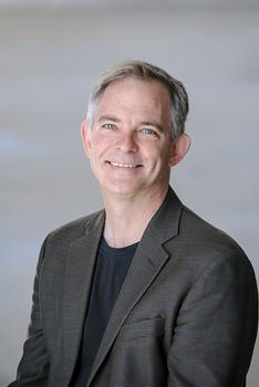 Solon Simmons is wearing a black T-shirt and a dark patterned blazer